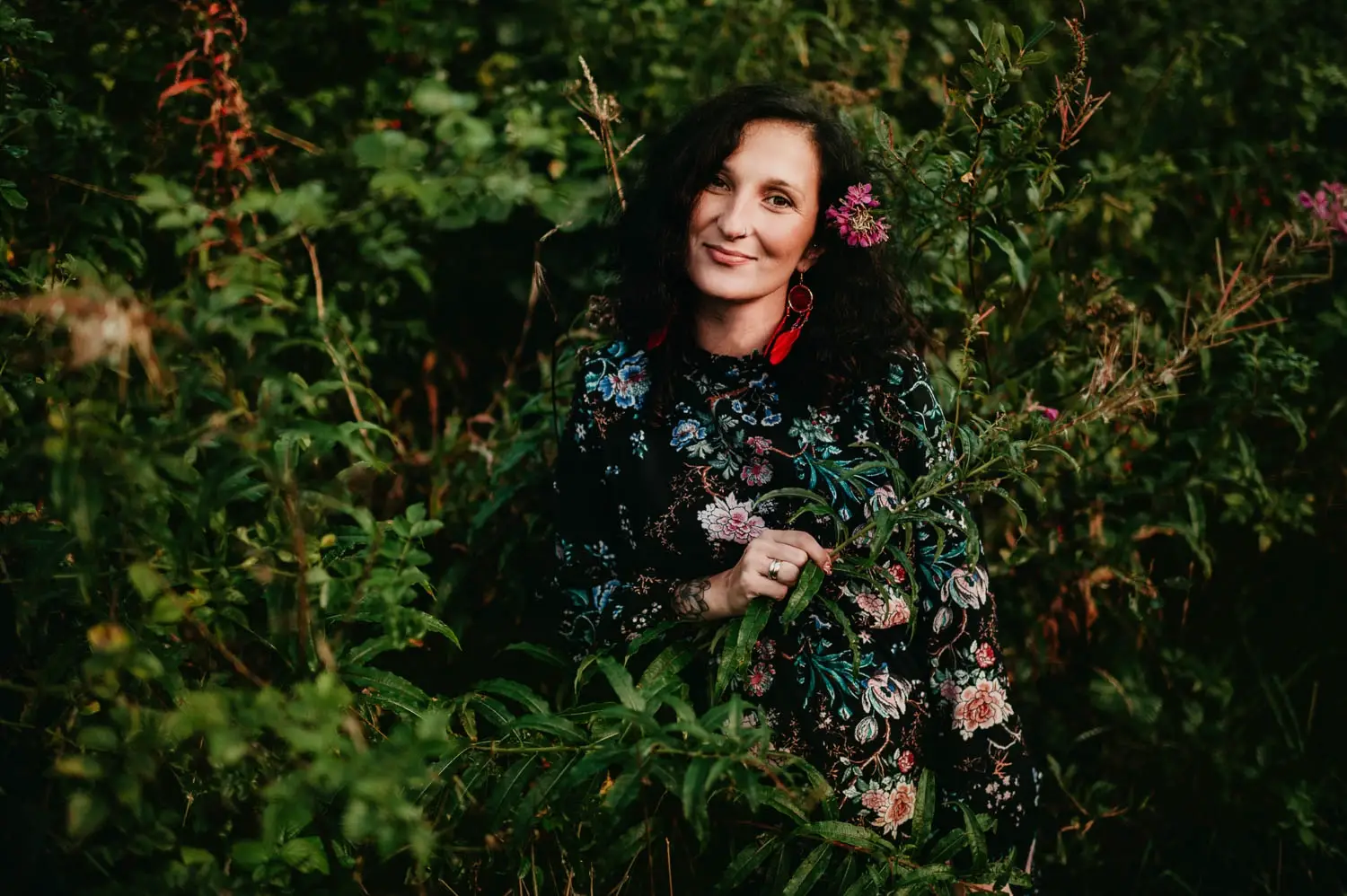 Kobieta w ciąży wśród kwiatów i zieleni podczas plenerowej sesji ciążowej