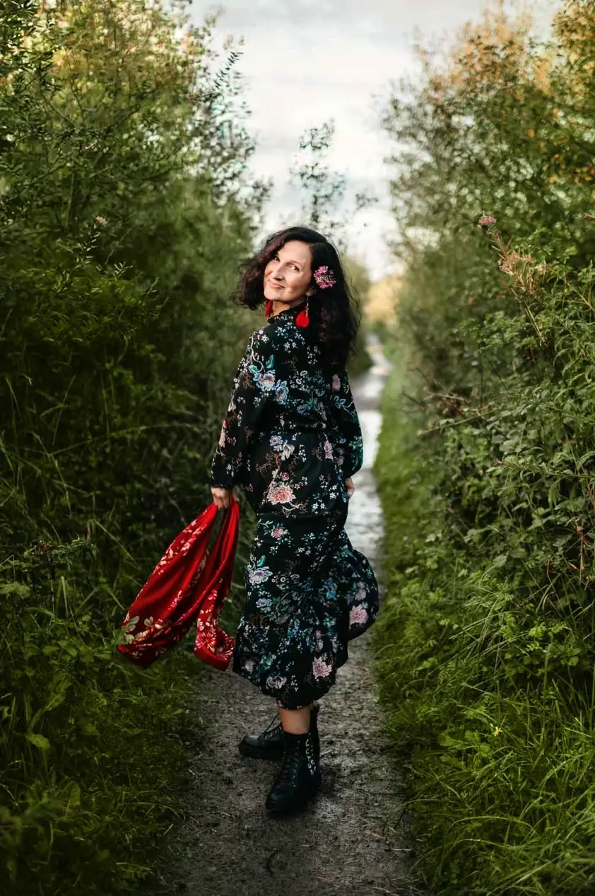 Kobieta w ciąży spacerująca ścieżką wśród zieleni podczas plenerowej sesji ciążowej w Krakowie