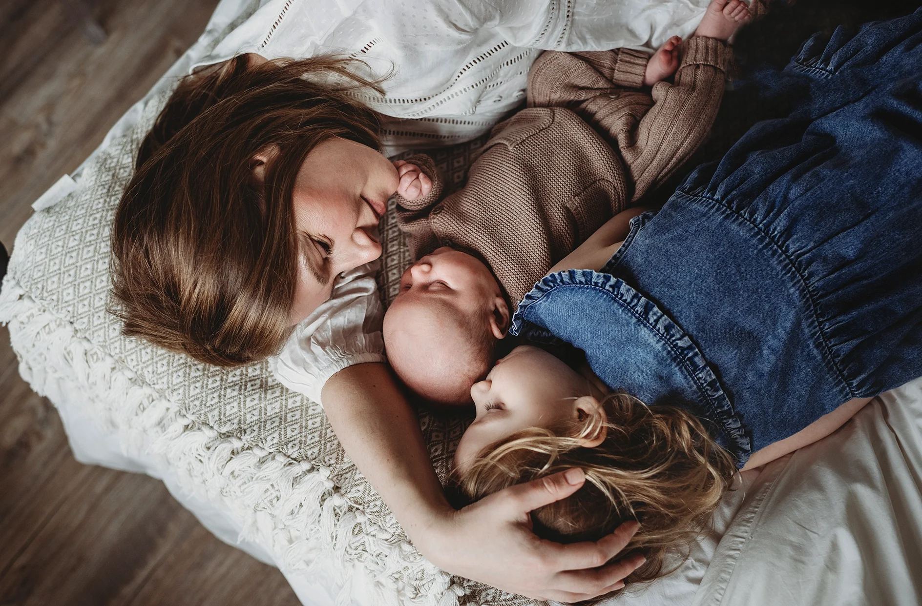 Mama z noworodkiem i starszą siostrą podczas rodzinnej sesji noworodkowej w Krakowie