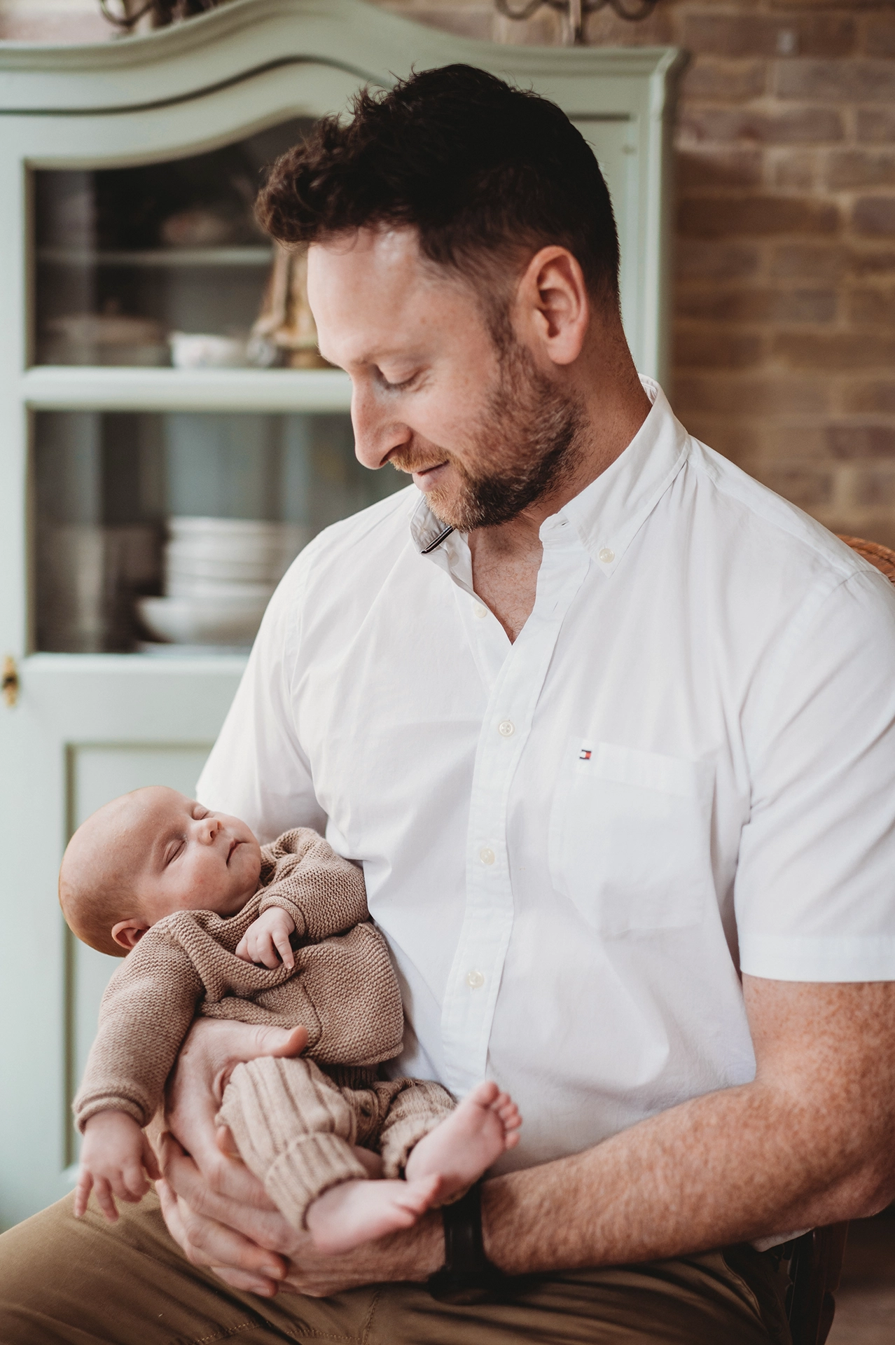 Tata trzymający noworodka na rękach podczas naturalnej sesji noworodkowej w Krakowie