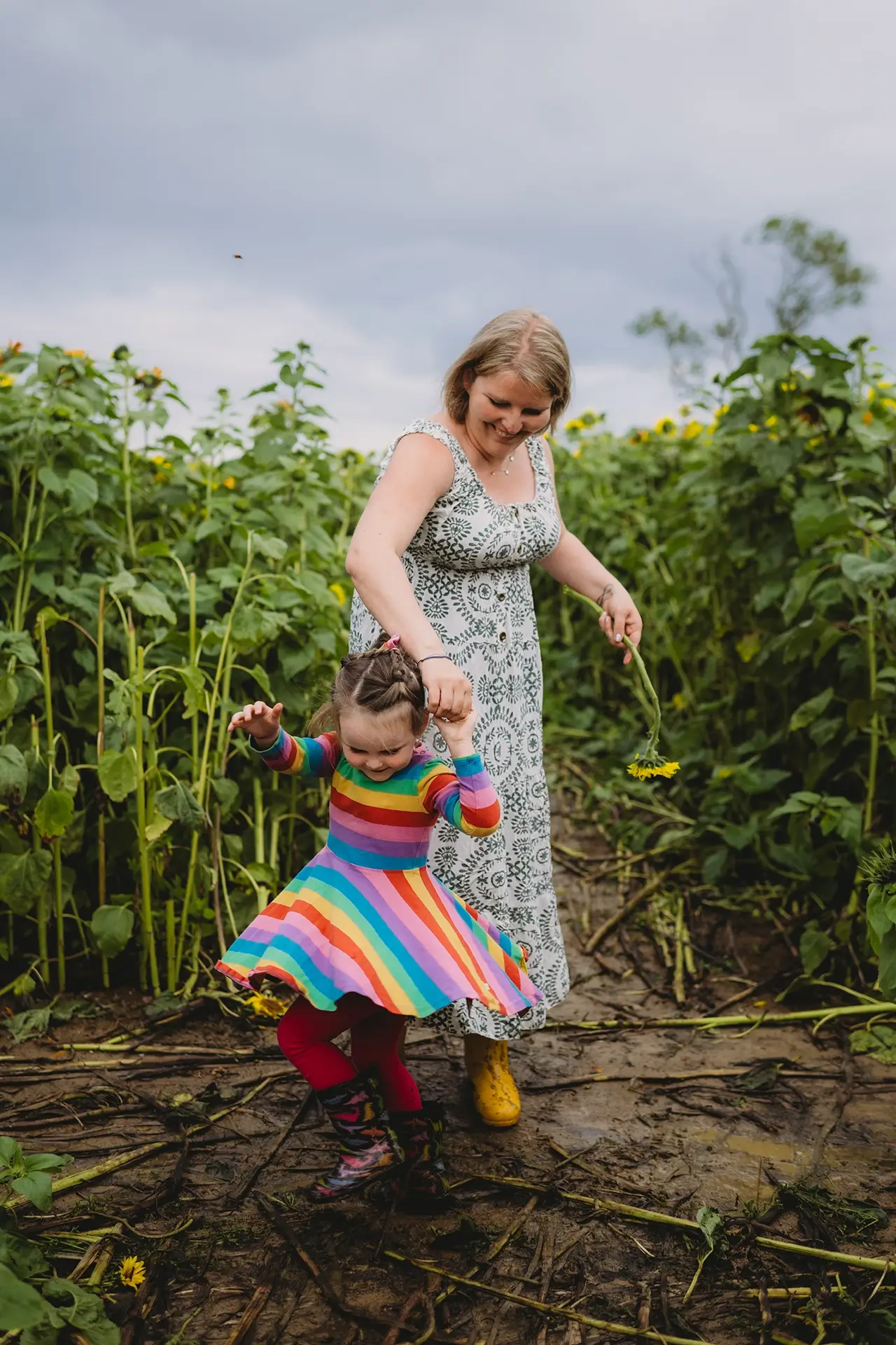 naturalna sesja rodzinna w plenerze - mama tańczy z córeczka w polu słoneczników